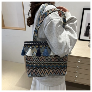 Close-up of bohemian woven tote bag showing intricate geometric patterns and colorful tassels