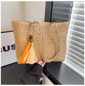 Detailed macro view of woven straw tote bag with orange tassels and wooden beads