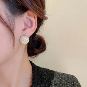Elegant gold plated shell stud earrings with shimmering zircons worn by a model