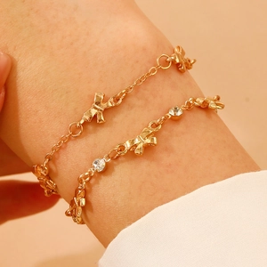 Detail of a layered gold bow bracelet with sparkling crystals on a woman's wrist
