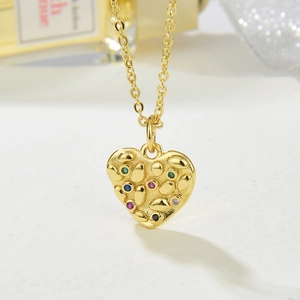 Detailed macro shot of a gold heart pendant necklace with colorful inlaid gemstones