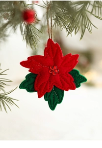 Close-up of red and green felt poinsettia flower ornament hanging on Christmas tree branch