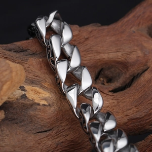 Detailed macro view of silver steel Cuban bracelet with floral engraving on wood