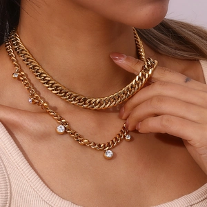 Detail of layered gold cuban chain and dainty necklace with round zircon pendants