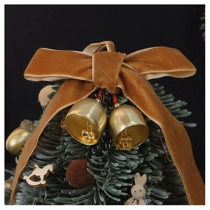Close-up of velvet bow with bronze metal bells and miniature Christmas tree ornaments