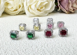 Macro shot of colorful Asscher cut silver stud earrings on textured white surface