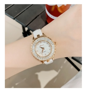 Close-up of luxury white ceramic watch with gold bezel and crystals on female wrist