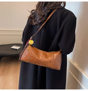 Detailed view of vintage brown crescent bag with vertical stitching and smiley tassel charm