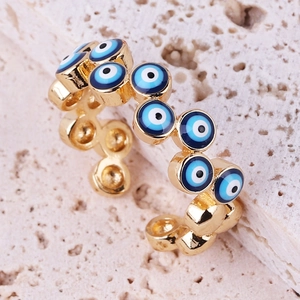 Macro shot of gold-plated evil eye ring showing blue enamel details and metal texture