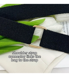 Detailed macro view of black woven shoulder strap with polished gold metal square rings