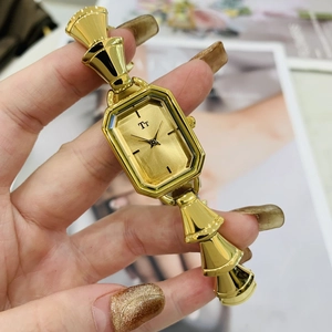 Dettaglio di un orologio dorato vintage con quadrante rettangolare e cinturino a bambù