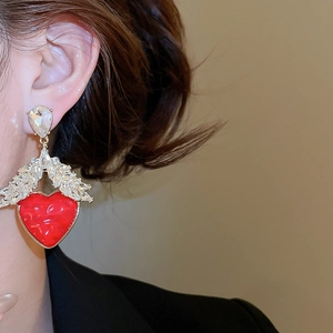 Détail de la boucle d'oreille cœur rouge marbré avec cristal sur l'oreille du mannequin