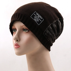 Close-up of brown knitted winter beanie with mixed grey pattern and branded fabric label