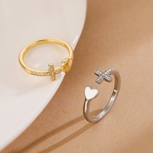 Detailed macro shot of gold and silver heart rings with zircon cross on white porcelain