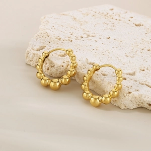 Minimalist gold beaded hoop earrings with a gradient design on white textured stone