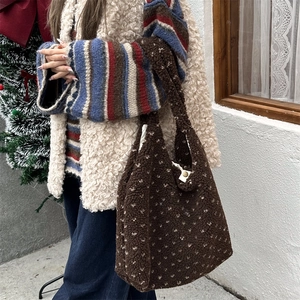 Close-up of brown faux fur tote bag with polka dots and snap button on winter background
