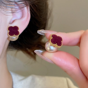 Detailed view of flocked burgundy flower earring with gold trim and pendant pearl drop