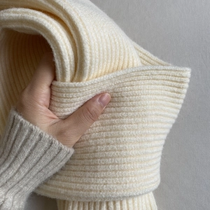 Close-up of cream white thick ribbed knit scarf showing soft premium wool texture