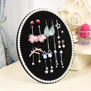 Macro view of velvet jewelry display stand featuring pearl border and assorted earrings