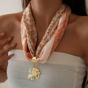 Detail of floral silk scarf with golden elephant pendant and colorful rhinestones