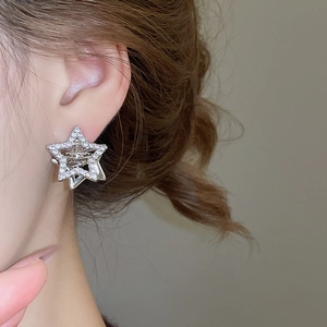 Macro detail of silver planet drop earrings featuring sparkling cubic zirconia on a model