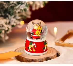 Close-up of a festive Christmas snow globe with a red base and bear figurine on wood