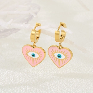 Détail de créoles dorées avec cœur en émail rose et pendentif œil protecteur