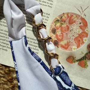 Détail de la chaîne dorée sur les bretelles de bikini avec motif géométrique bleu