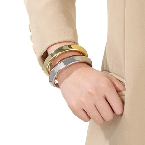 Gros plan de bracelets larges minimalistes dorés et argentés portés par un mannequin