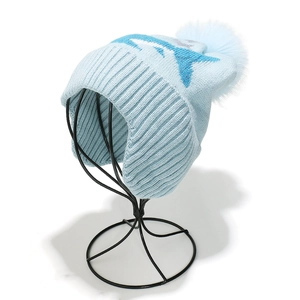 Close-up of light blue knitted hat featuring soft ribbing and fluffy faux fur pom-pom