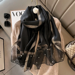 Detail of black silk scarf with gold metallic stripes and elegant white pearl accents