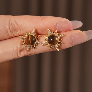 Detailed view of gold sunburst stud earrings with tiger eye stone and crystal zircon
