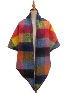 Detail of multi-color plaid poncho shawl on wooden mannequin with textured knit fabric