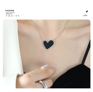 Close-up of a dark acrylic heart pendant necklace worn on a model's collarbone