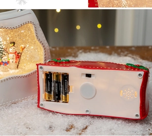 Detail view of the battery compartment and power switch on a Christmas snow globe lantern