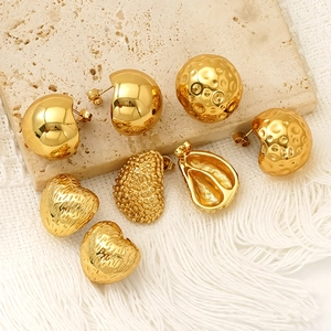 Golden chunky metal earrings in geometric, heart, and teardrop shapes on stone background