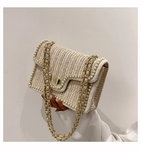 Detail of straw woven bag with pearl trim, V-shaped texture and gold chain strap