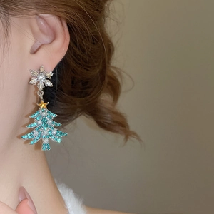 Close-up of Christmas tree earring with green rhinestones and pearl on model's ear