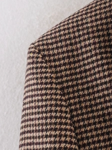 Detailed view of shoulder stitching on a brown houndstooth mid-length blazer coat