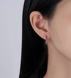 Macro side view of U-shaped rainbow gemstone earring with 14k gold plating on model