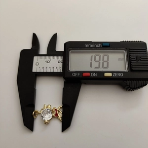 Detail shot showing a gold elk pendant width measurement of 19.8mm using digital calipers
