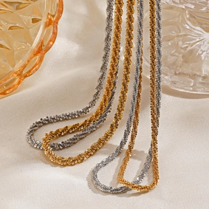 Sparkling gold and silver stainless steel chain necklaces draped on beige fabric