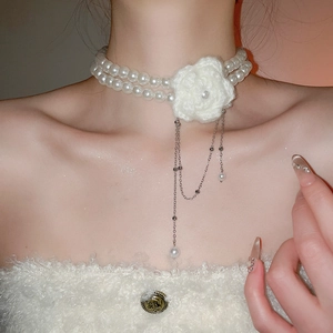 Détail du ras-du-cou double rang de perles avec fleur tricotée et pampilles argentées