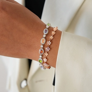 Close-up of stacked elegant bracelets with colorful gemstones, pearls, and flower charms