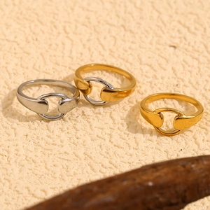 Polished 18K gold and silver interlocking buckle rings on a natural stone textured background