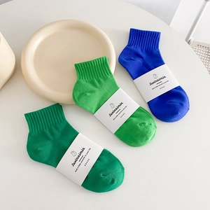 Tre paia di calzini di cotone verde e blu reale con polsini a costine su superficie bianca