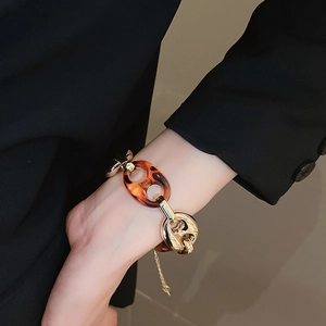 Dettaglio del bracciale a maglie dorate e resina leopardata indossato al polso