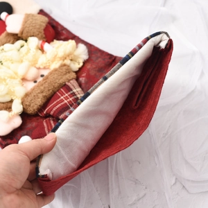 Detail view of a red felt Christmas stocking with a 3D Santa doll and plaid fabric trim