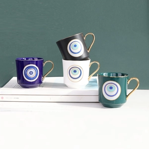 Detail of four colorful ceramic evil eye mugs with golden handles and gold-rimmed edges