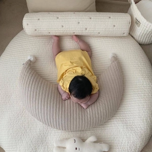 Detail of quilted cotton moon pillow and round play mat for baby nursing in beige color
